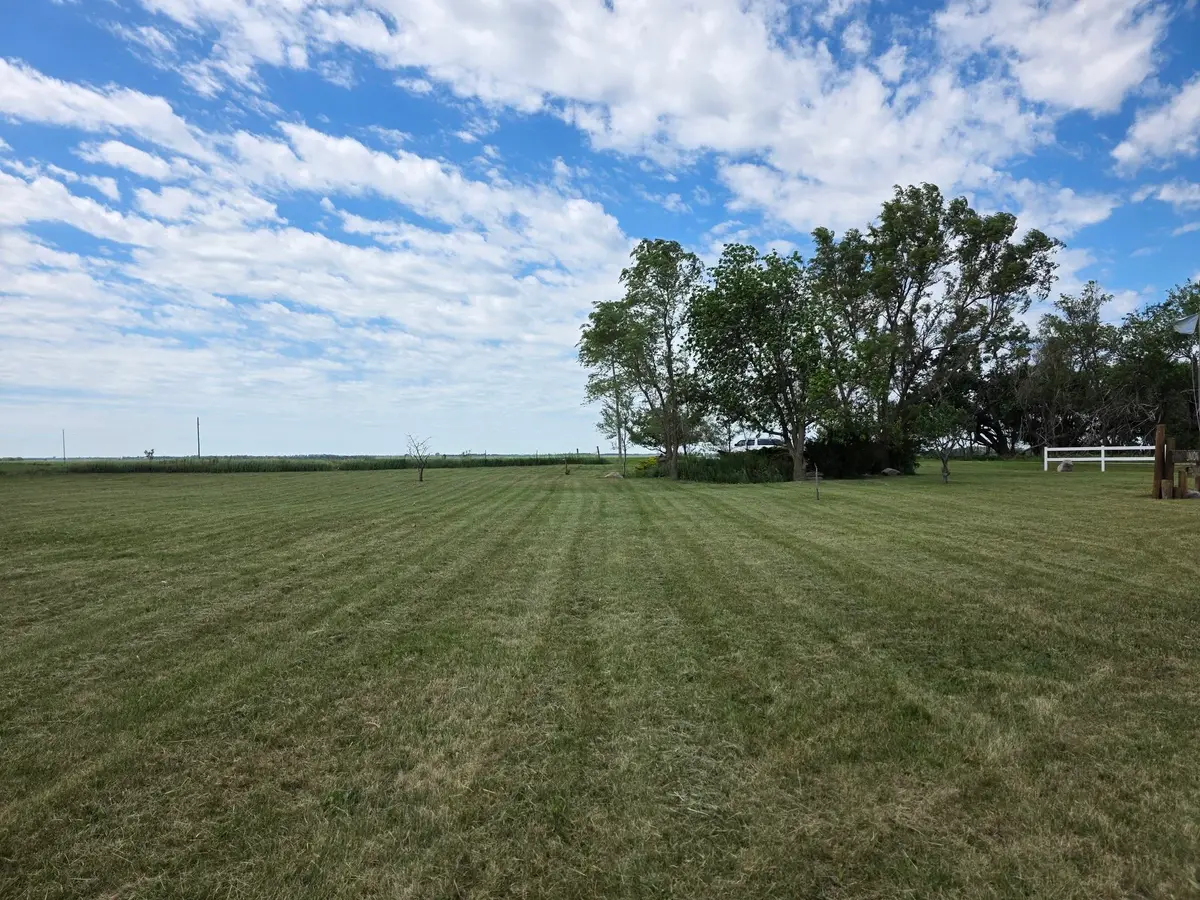A big open lawn near Mount Vernon, freshly mown in straight stripes under a blue prairie sky